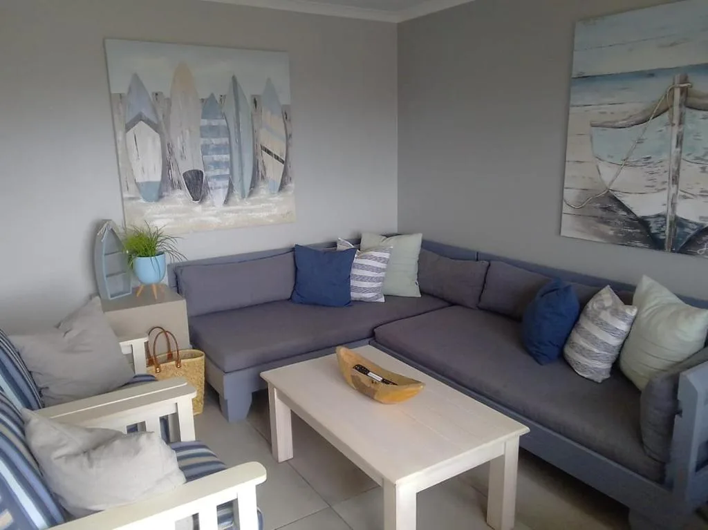 Modern lounge with grey sectional sofa, blue cushions, and coastal artwork