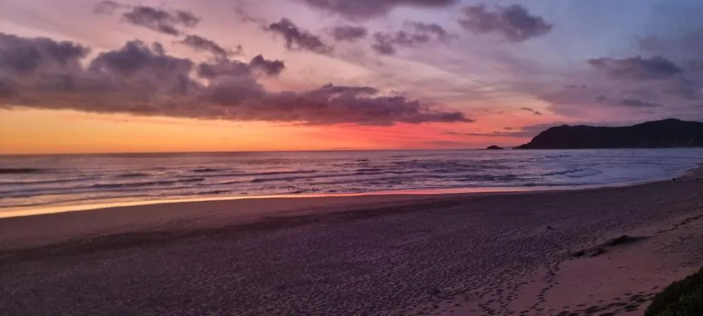 Stunning sunset over ocean beach with purple and orange sky