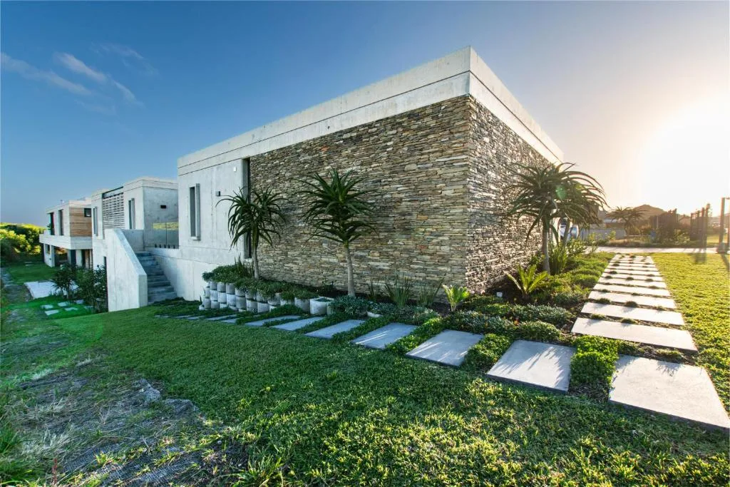 Modern white and stone vacation home with manicured gardens and pathway