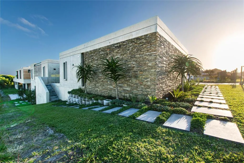 Modern white and stone beach house with manicured gardens and pathway