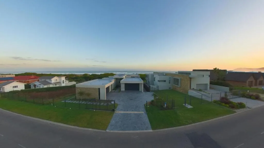 Modern beachside property exterior with driveway, manicured lawn, and coastal views
