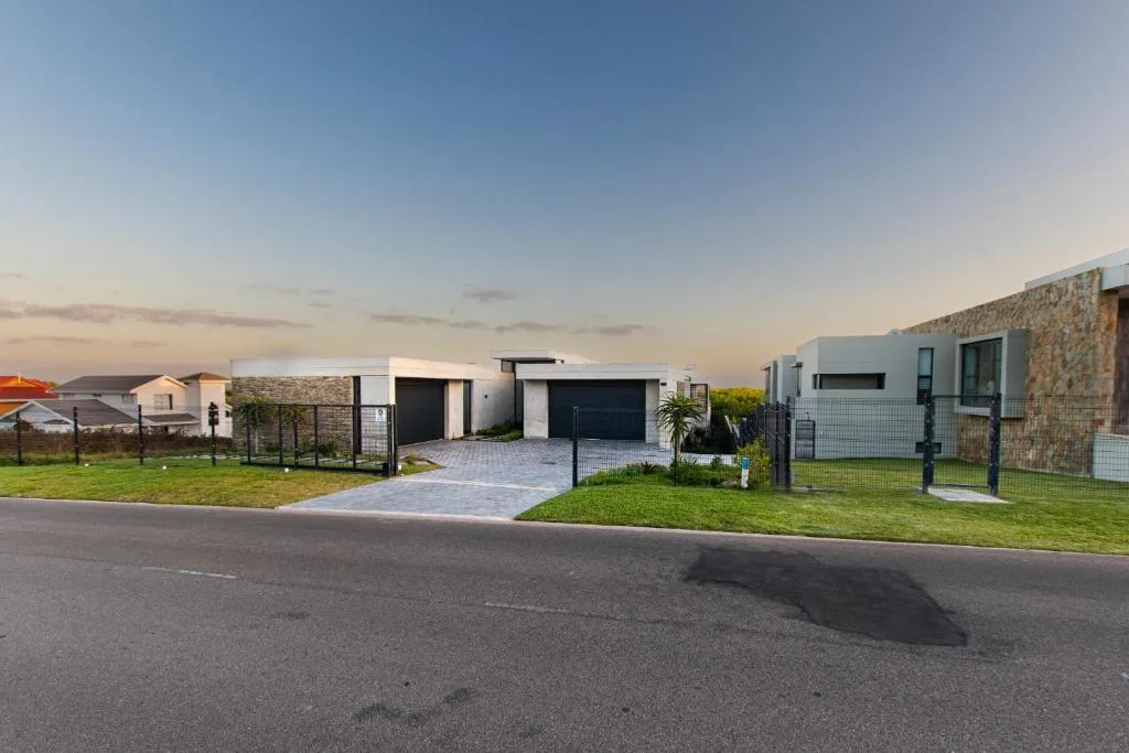 Modern white house with black garage gates and manicured front lawn