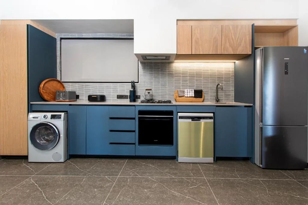 Modern kitchen with blue cabinetry, stainless steel appliances, and washing machine