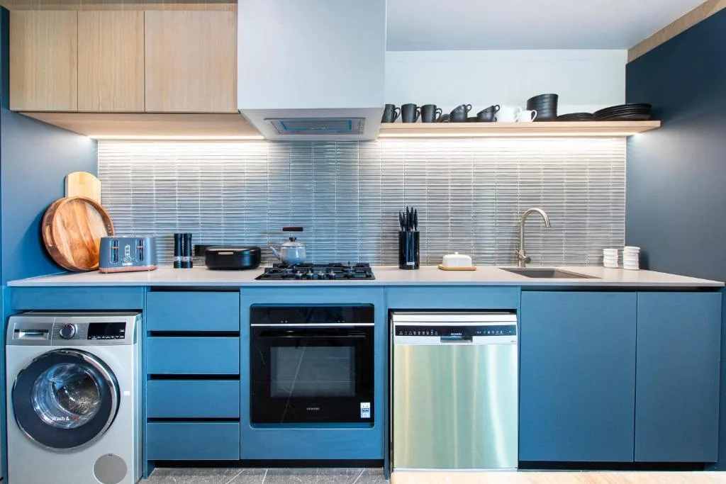 Modern kitchen with blue cabinetry, gas cooktop, oven, and dishwasher