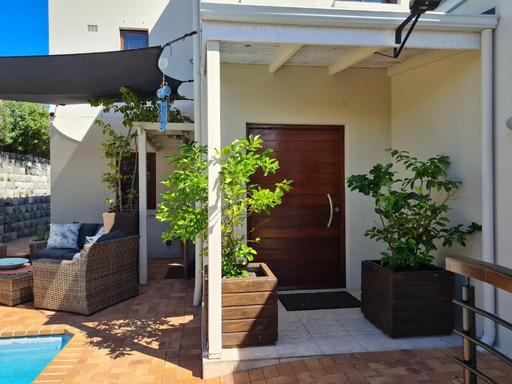 Covered patio area with comfortable seating and potted plants near entrance