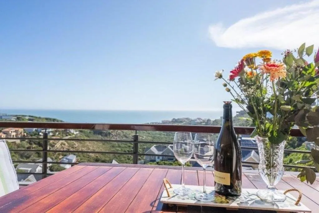 Wooden deck with ocean and coastal views, wine bottle and flowers
