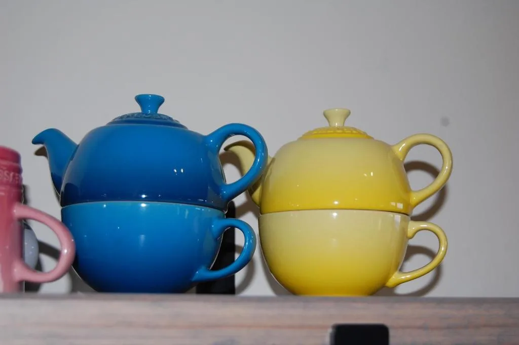 Colorful ceramic teapots and cups displayed on shelf
