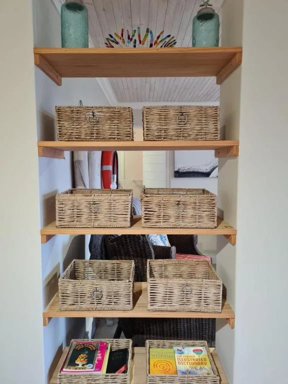 Wooden shelves with wicker baskets, towels, decor and books