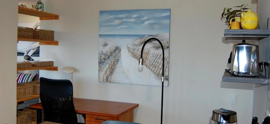 Workspace with desk, shelving, and beach pathway artwork decoration