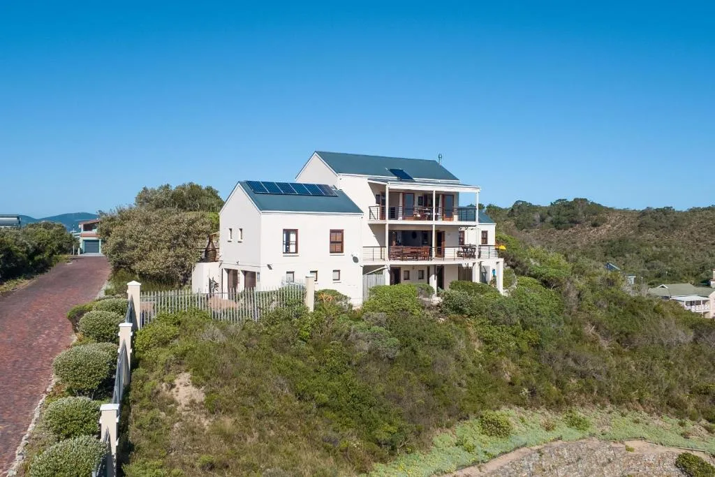 Modern white holiday home perched on hillside with solar panels and decks