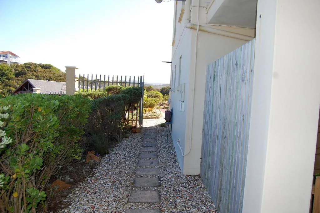 Side pathway with gravel and stepping stones leading to property entrance gate