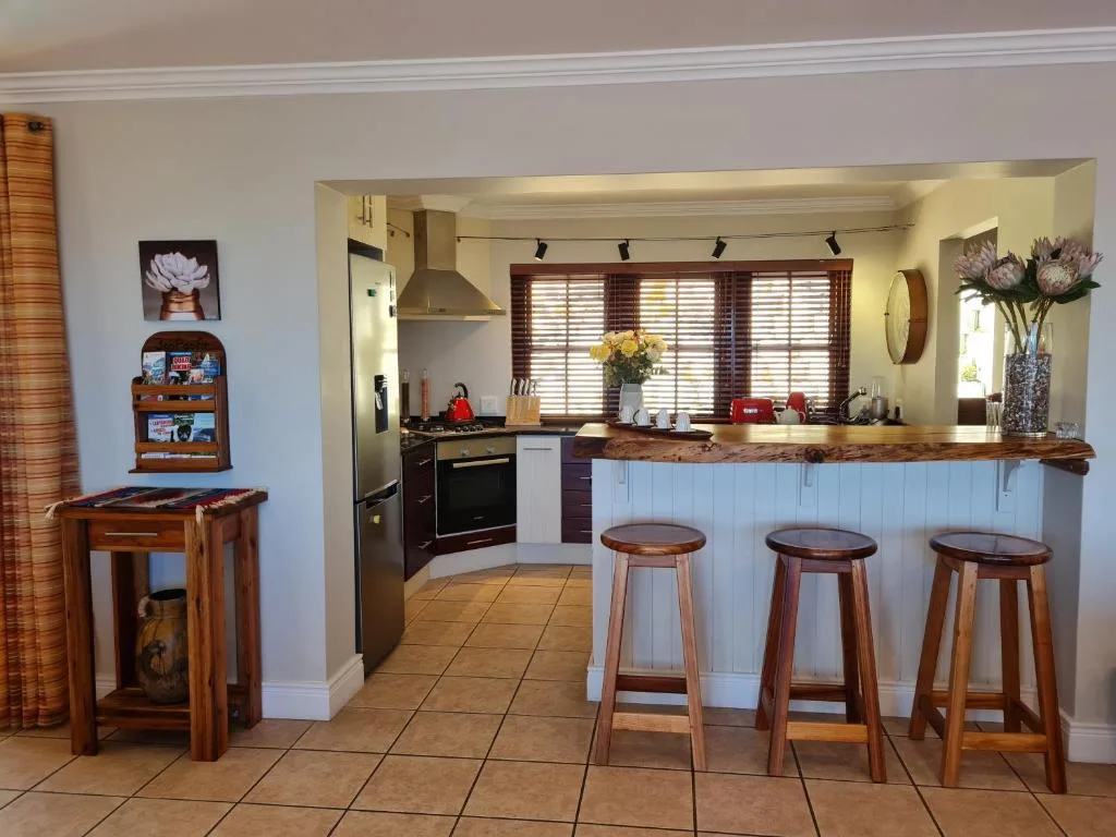 Modern kitchen with white cabinetry, wooden bar stools, and pendant lighting