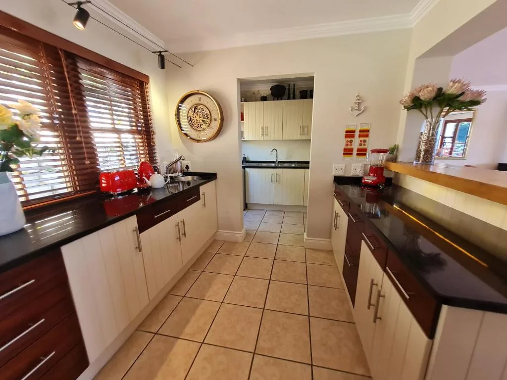 Spacious galley kitchen with white cabinetry, black granite counters, and tiled flooring