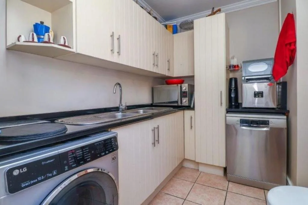 Modern kitchen with white cabinetry, stainless steel appliances, and black countertops