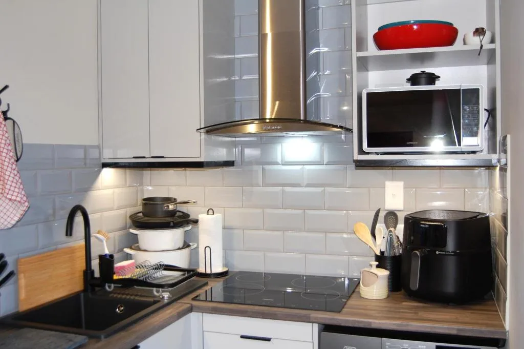 Modern kitchen with white cabinetry, stove, microwave, and wooden countertops