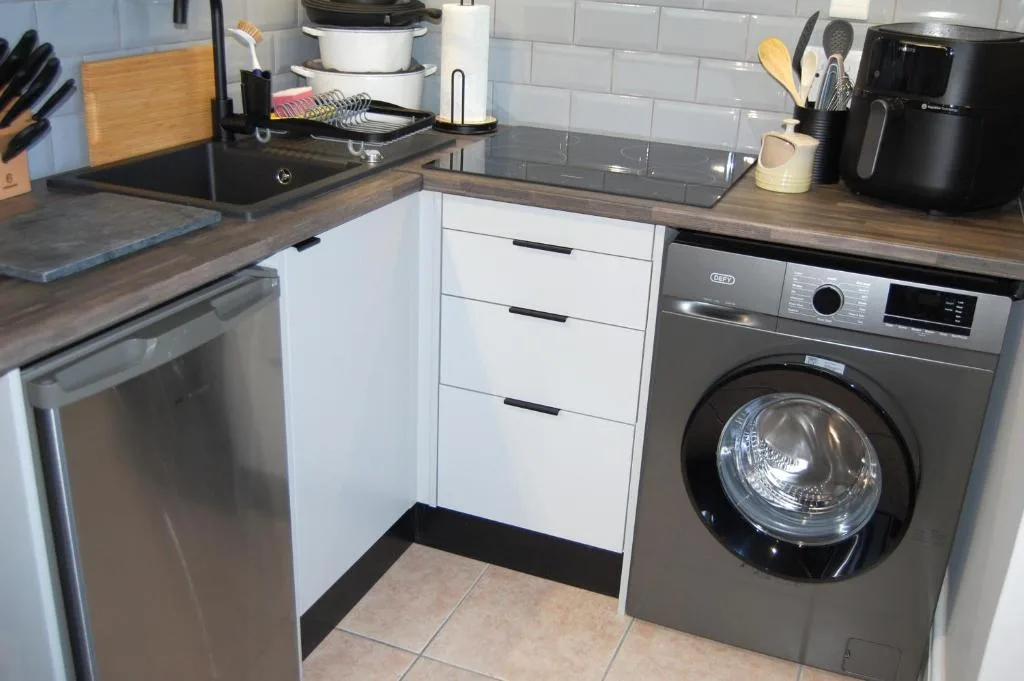 Modern kitchen with stainless steel appliances, white cabinetry, and wooden countertops