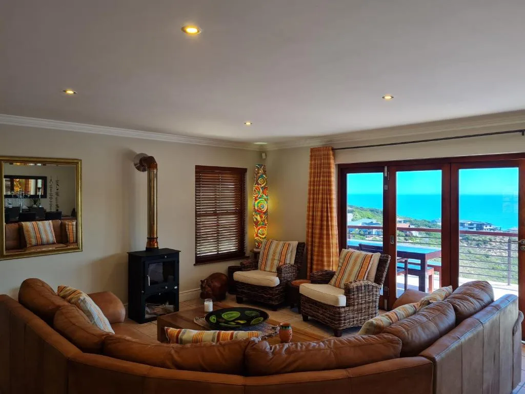Spacious lounge with leather sofa, fireplace, and panoramic ocean views