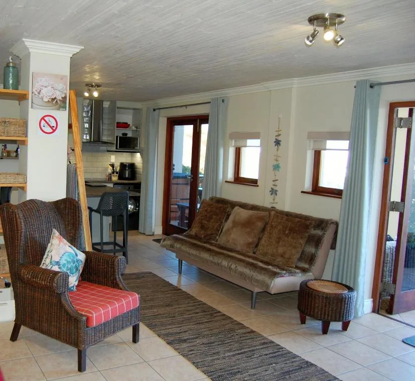 Open-plan lounge with brown sofa, wicker chairs, and kitchen visible