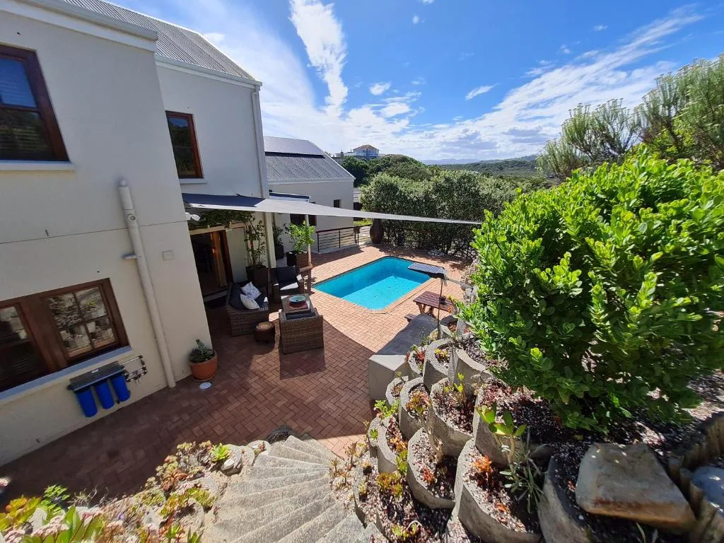 Bright blue swimming pool surrounded by brick patio and lush landscaping