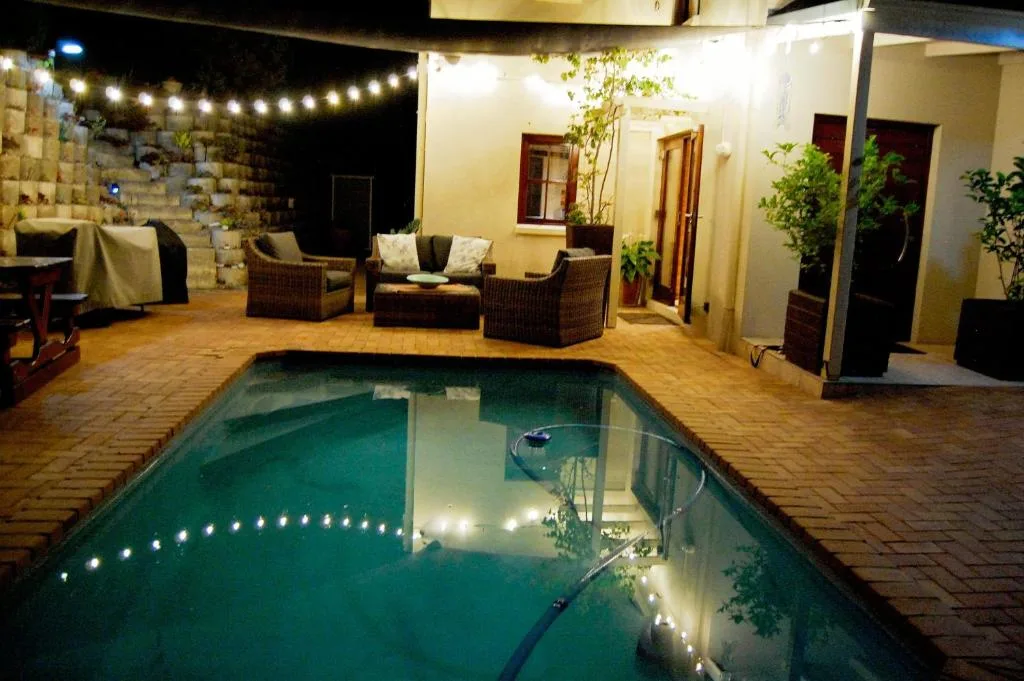 Illuminated swimming pool at night with lounge seating and patio area
