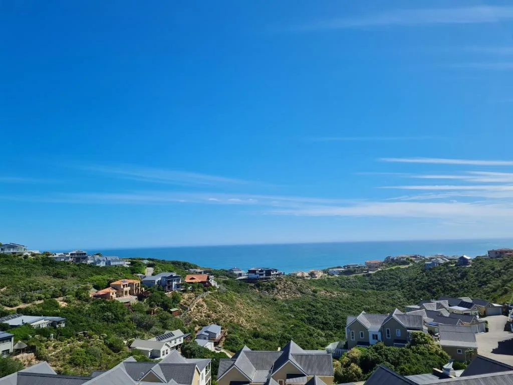 Panoramic coastal vista with houses nestled on hillside overlooking ocean