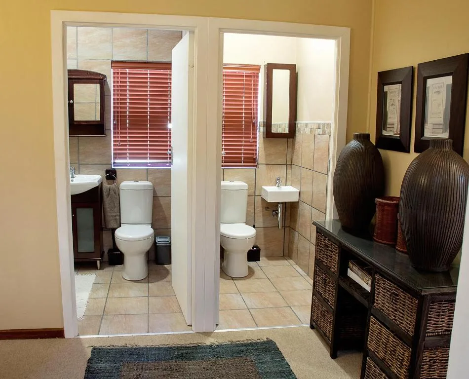 Twin bathrooms with toilets, vanities, and red venetian blinds for privacy