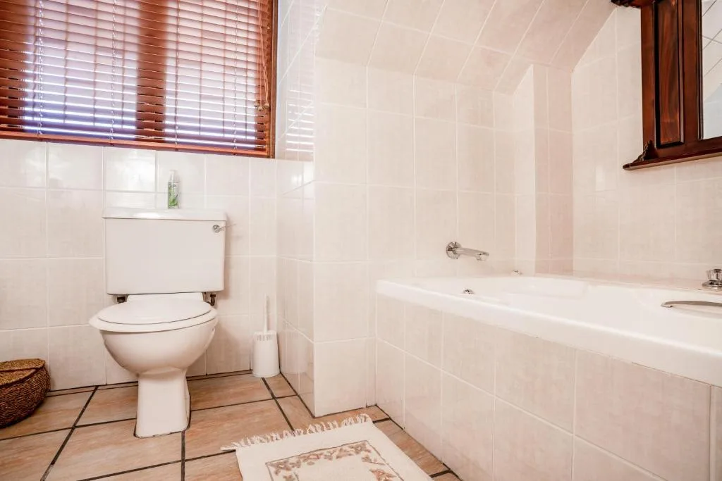 Clean bathroom with toilet, bathtub, and tiled walls with wooden window
