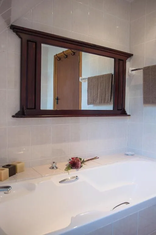 Modern bathroom vanity with dark wood-framed mirror and white subway tiles