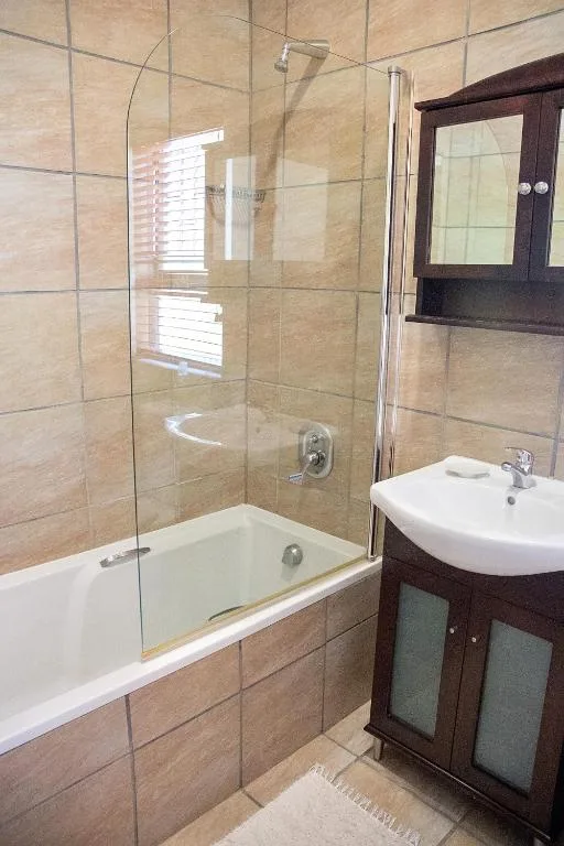 Modern bathroom with glass-enclosed shower, soaking tub, and dark wood vanity