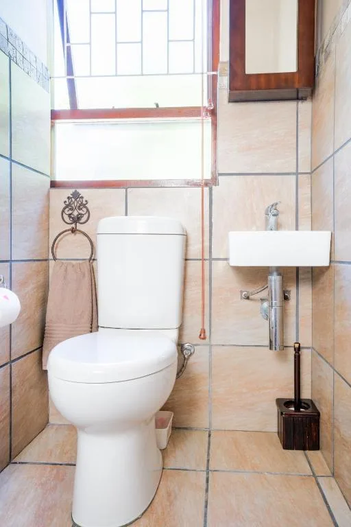 Compact bathroom with white toilet, wall-mounted sink, and tiled walls
