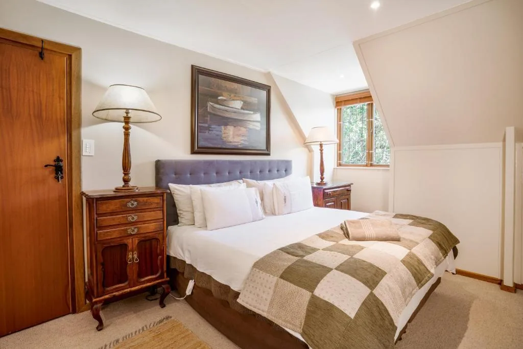 Bright bedroom with queen bed, plaid bedding, wooden nightstands, and reading lamps