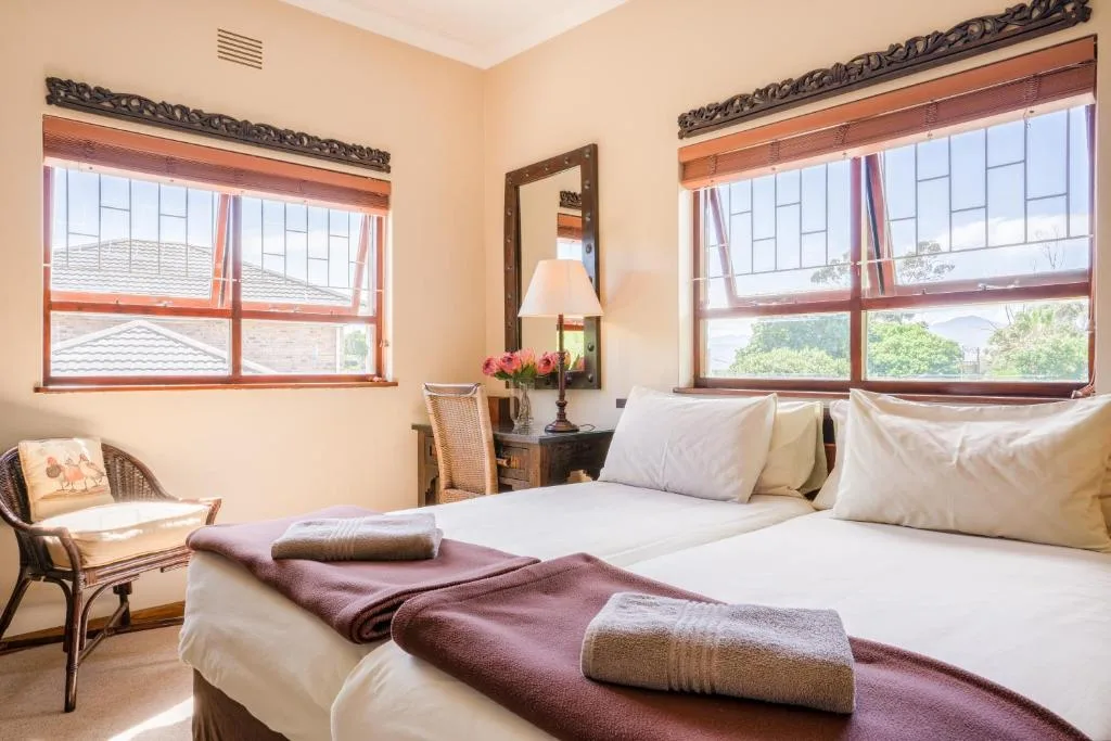 Bright bedroom with twin beds, decorative mirror, and mountain views through large windows