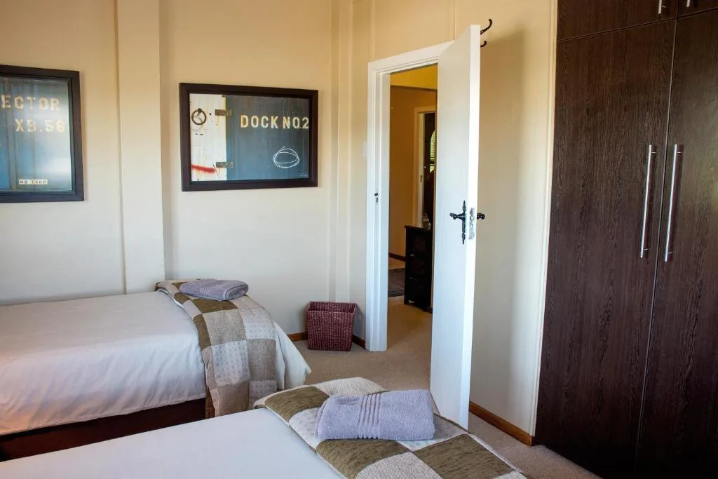 Bright bedroom with two beds, wardrobe, and framed nautical artwork