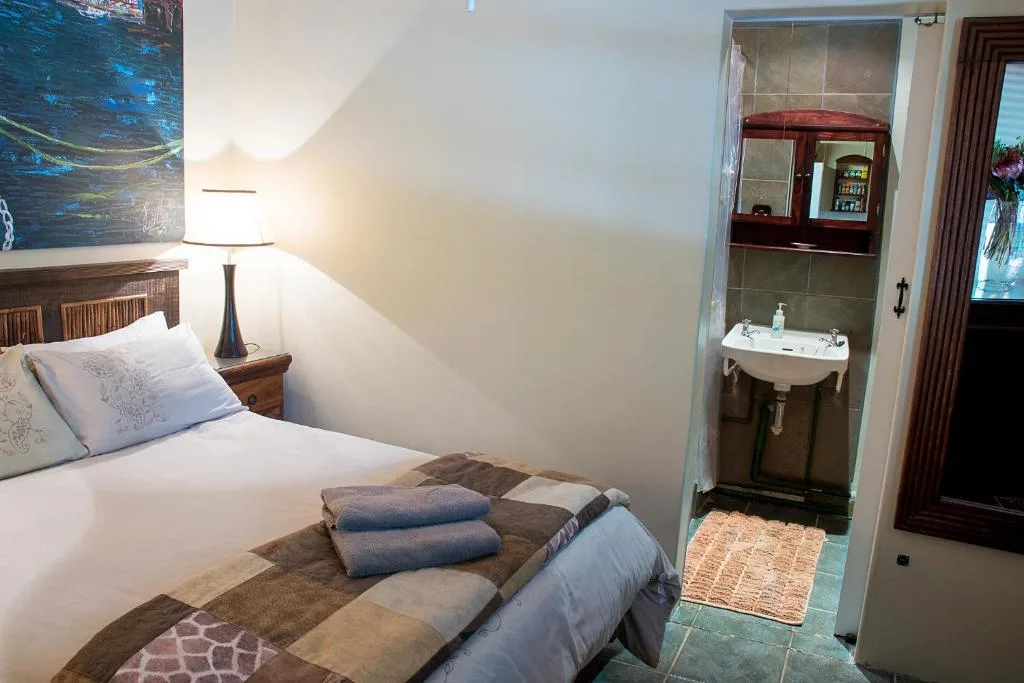 Bedroom with bed, bedside lamp, and ensuite bathroom visible through open door