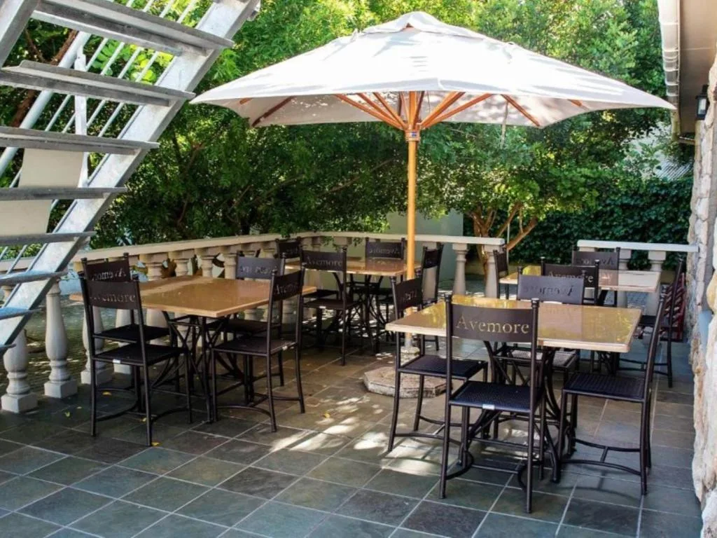 Outdoor dining area with umbrella and wooden tables on paved patio