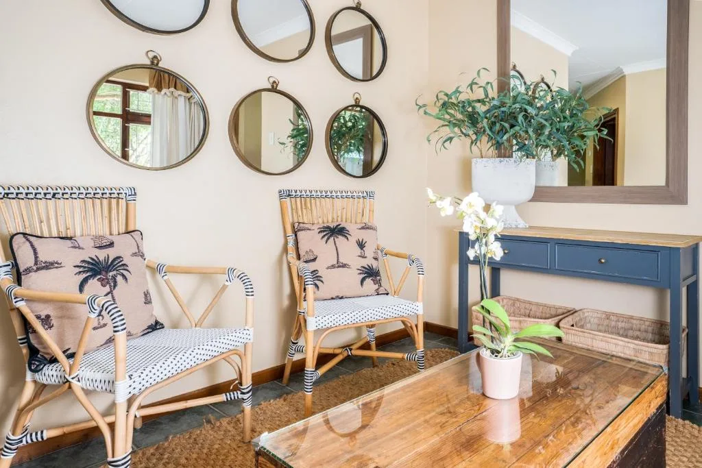 Stylish lounge decor with woven chairs, hanging mirrors, and potted plants