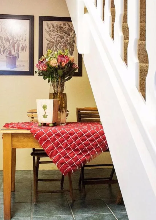 Cozy nook with wooden table, red blanket, fresh pink flowers in vase