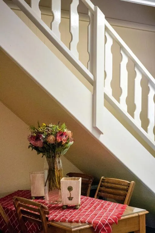 Flowers in vase on red checkered table under white staircase