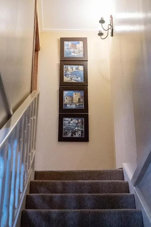 Stairwell with framed coastal photographs and contemporary wall sconce lighting