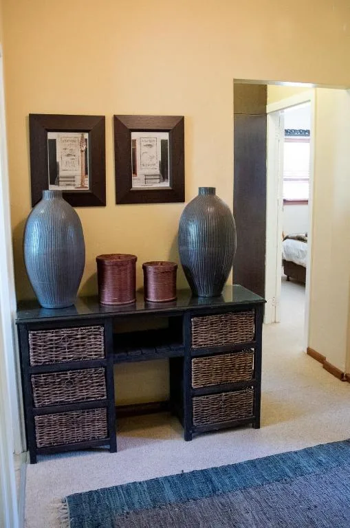 Decorative desk with blue vases, candles, and framed artwork on yellow wall