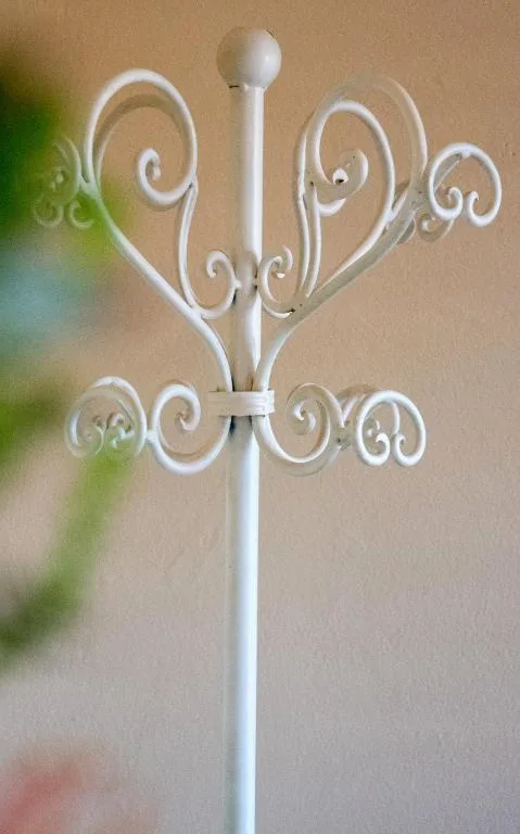 White decorative coat rack with ornate scrollwork and curved hooks