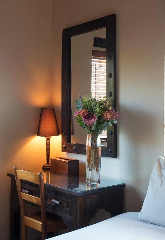 Bedroom vanity with mirror, lamp, fresh flowers, and wooden chair