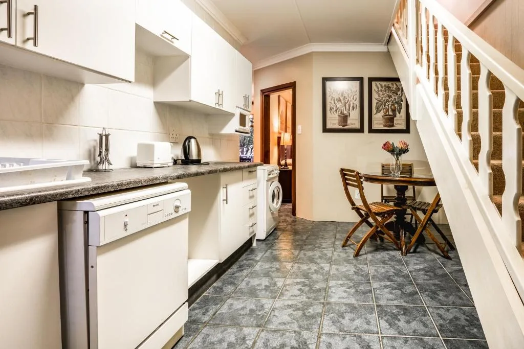 Modern white kitchen with granite countertops, stainless steel appliances, and dining area