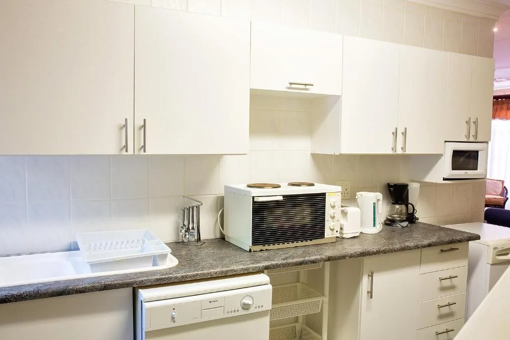 Modern kitchen with white cabinetry, granite countertop, and appliances