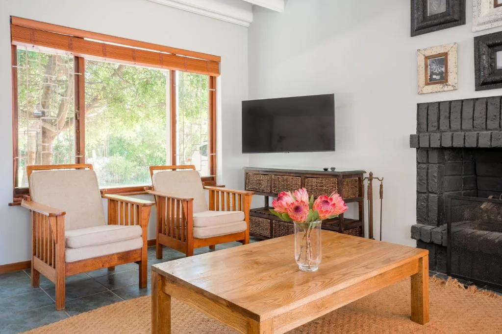 Bright living room with wooden furniture, fireplace, and garden views