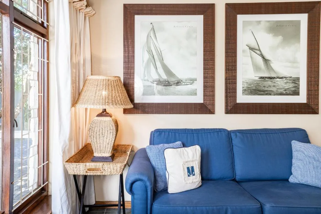 Blue sofa with cushions, wicker lamp, and nautical sailboat artwork