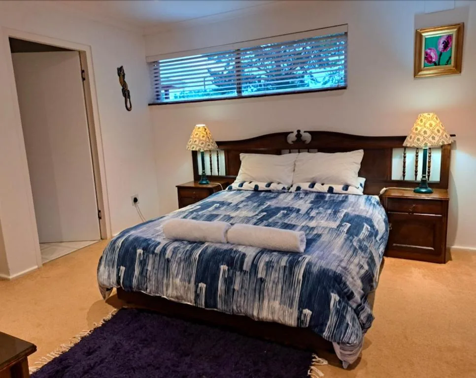 Spacious bedroom with queen bed, dark wood headboard, bedside lamps and furniture