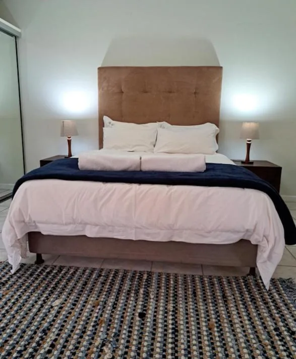 Spacious bedroom with upholstered headboard, white bedding, and bedside lamps