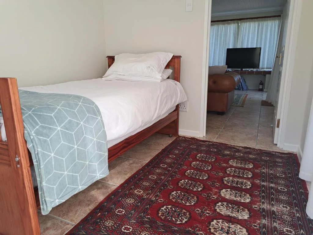 Single bed with white linens and patterned throw in spacious bedroom