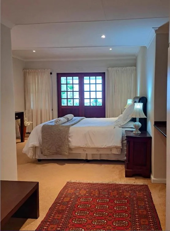 Spacious bedroom with queen bed, dark wood furniture, and large windows
